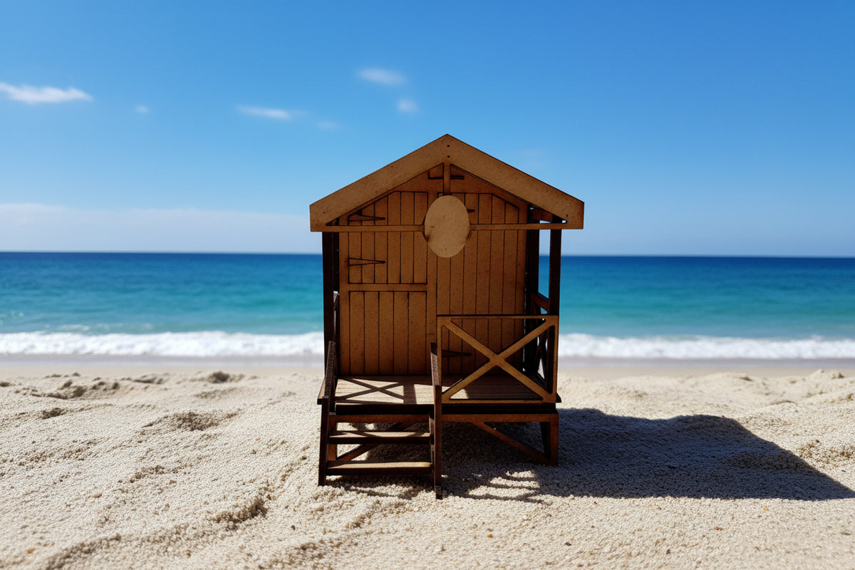 A 1:43 scale model of a beach hut made of wood, featuring detailed construction including a thatched roof and a deck area with chairs.