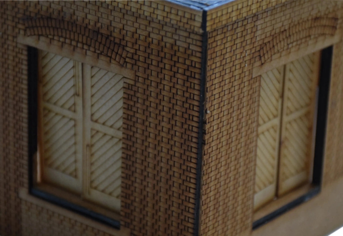 Rail Model Rhoystellen Station Goods Shed, 4 mm scale—close-up of the assembled laser-cut MDF brick structure, focusing on the corner junction with detailed brick courses, arched lintels, and diagonally-planked sliding goods doors.