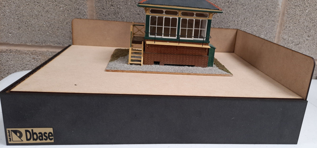 A diorama base made of MDF in flat pack, featuring a model train depot on top, with a black outer section and a gray inner lining.