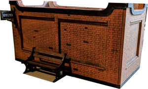 A model of a station platform bench made from MDF, painted and placed on a layout with a brick wall in the background.