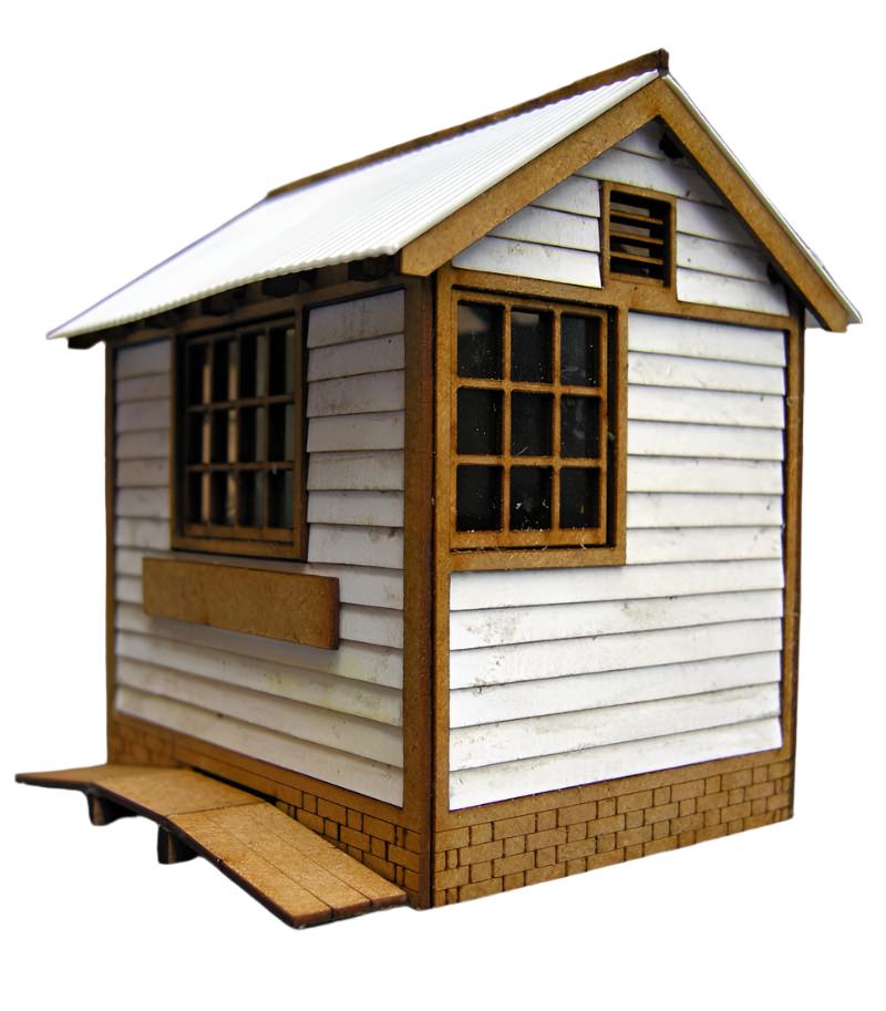 A model of a small ground frame hut with corrugated plastic roofing, wooden-like details, and a window with film applied to its panes.
