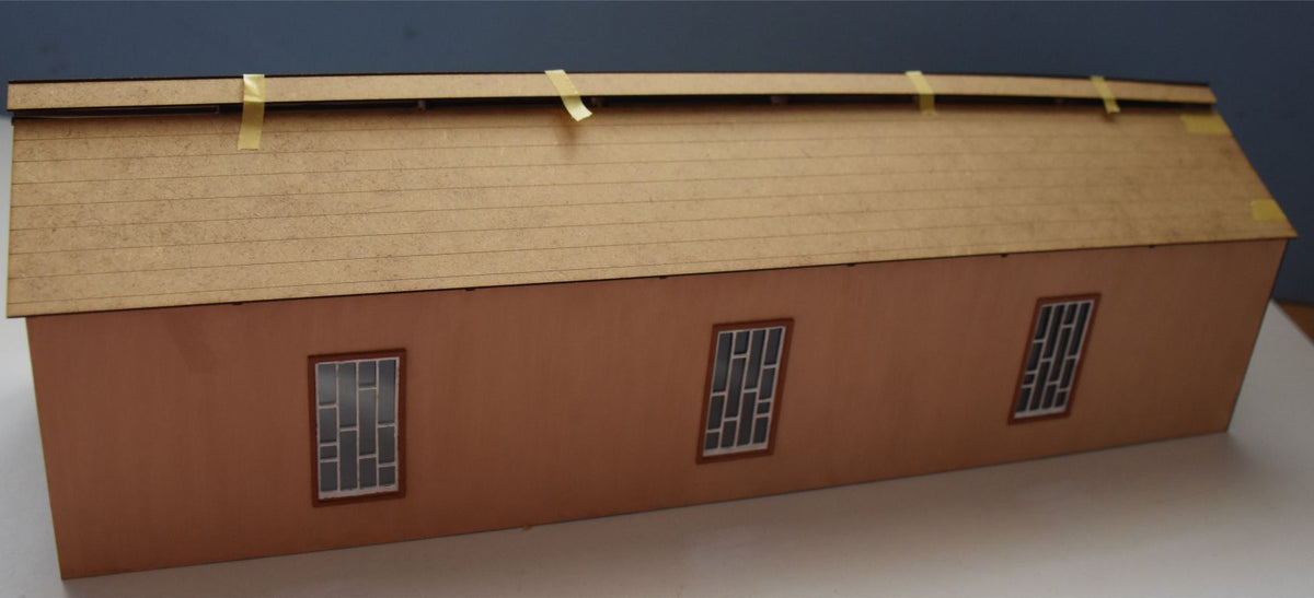 A model of a carriage shed with a tiled roof, designed for model train sets.