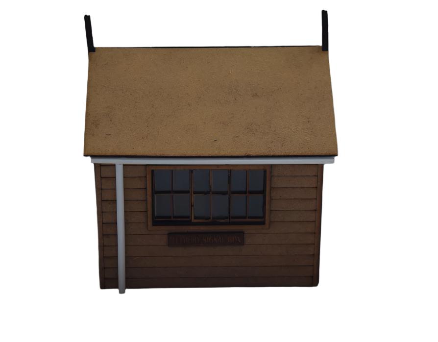 A laser cut and engraved model of a signal box with a brown roof, gray walls, a window with black film, and a gutter and downpipe.