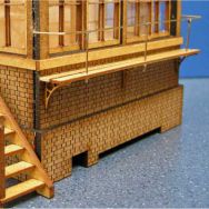 A brass rod used for model making, displayed on a blue background, with a model building showing the rod's potential use for hand rails.